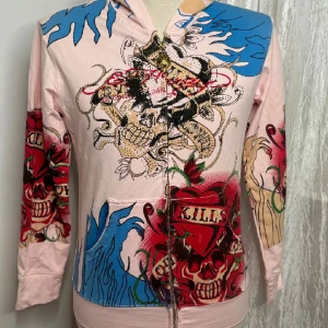 Ed hardy hoodie - Köpte på vinted, helt ny med lapp på.  Är storlek xxl men passar xs-m.  Färgen på hoodie har rosa undertoner, så inte vitt. Helt ny skick, använde den aldrig eftersom jag inte tycker den var fin på mig 💕  (Bilderna är från förra säljaren) 