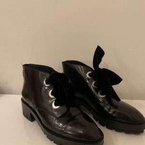 Boots från Sandro Paris - Lackade boots från Sandro Paris. Storlek 39 med söta sammetsrosettband
