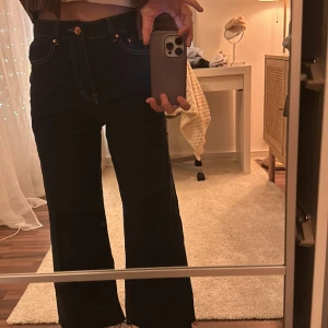 Jeans - Mörkblåa jeans som slutar vid anklarna! Blir bredare och bredare med längden! Guld detaljer! :) oanvända ( men provade ) 