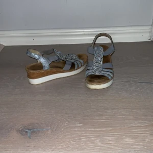 Sandaler  - Fina blå sandaler med lite strass, lite klack på ca 5 cm. Bra skick men använda några gånger