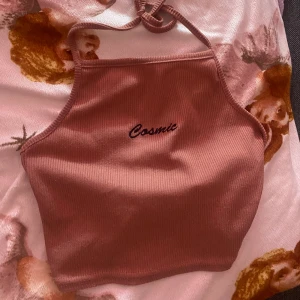 Croptop med tryck - Säljer en croptop (som jag tror är från pretty little thing) som man knyter runt halsen. Har tryck ”cosmics” och en väldigt fin färg, rosa-violett eller nåt liknande åt det hållet.