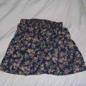 Svart kjol med rosa/bruna blommor. Har ALDRIG använts. Kjolen är från Temu.  Köpt för 54kr säljer för 20