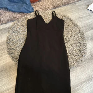 Klänning  - En svart vanlig klänning med en slits längst ner i mitten där bak. 