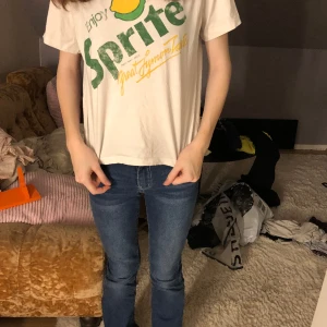 Sprite tröja - En vit tröja med en grön text där de står enjoy Sprite och trade mark regd litet och den en gul text där det står great fimen taste och en citron och en lime uppe över allt