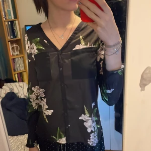 Mönstrad blus  - Jag säljer denna blus. Den är blommig på framsidan och randig på baksidan. Den är i utmärkt skick. 