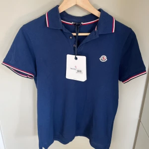 Moncler kortärmad piké logo mörkblå - Nyligen köpt piké från NK Göteborg, väldigt bra skick (9,5/10) och enbart använd fåtal gånger. Säljer för den sitter lite tajt på mig. Pris kan självklart diskuteras! 
