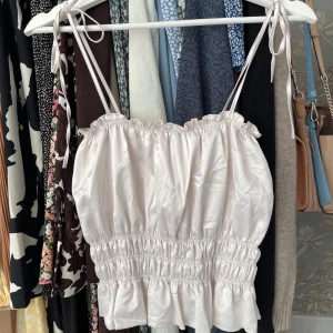 Vit/biege glansig topp med knytning - Vit/beige/grå lite glansig topp som är helt oanvänd från Zara, knytning i banden. 