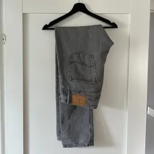 Ett par grå jeans från Jack & Jones. Relativt använda men i bra skick förutom ett litet slitage längst med vid ett av benen, därav lågt pris