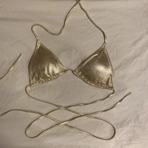 Bikini  - Guldig bikini med långa snören. Använt fåtal gånger. Passar cirka A-C kupa beroende på hur mycket man vill täcka 