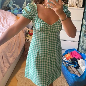 Grön rutig klänning  - Supersöt klänning i tunnt, luftigt material. Ganska kort. Använd kanske 5 gånger.  Knappar längst med klänningen 