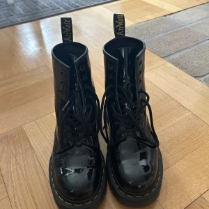 Höga och glansiga dr martens - Köpte dem för ungefär 2 år sedan med ett nypris på 1800kr. Har bara använts några få gånger men har en vit fläck längst fram på den ena som inte går att ta bort. Jag säljer dem på grund av att de inte kommer till användning. Skriv för mer bilder💗