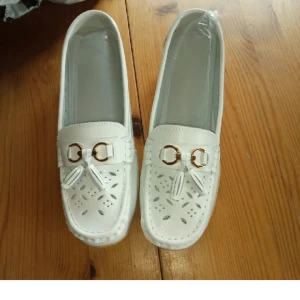 Skor mönstrad med tofsar stl 40. - Helt nya och oanvända skor mönstrade med tofsar ,mjuka och sköna för foten med liten klack. Stl 40.