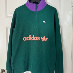 Adidas tröja - Oversized tjocktröja från adidas. Använd typ 2 gånger, storlek M.  Grön med lila och rosa detaljer.  Köpt för 700kr