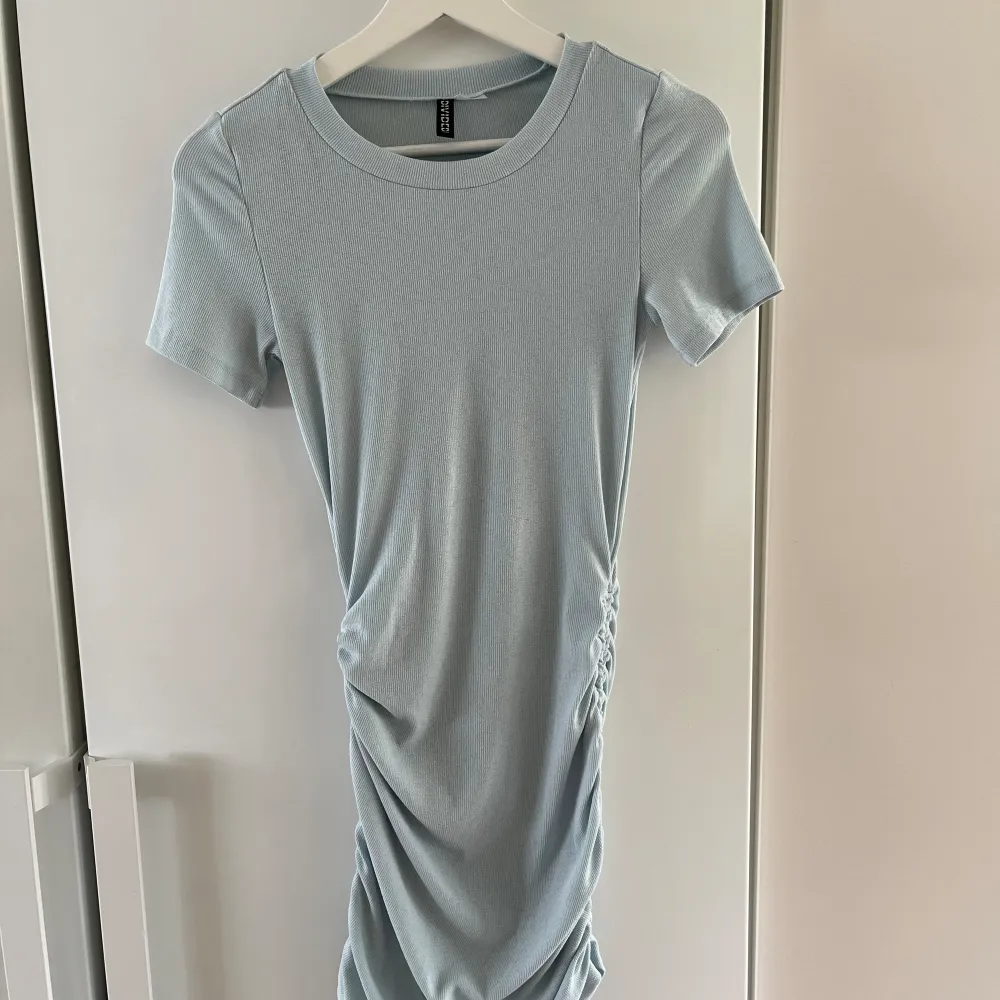 Ljusblå klänning från HM. Knytning i sidorna som gör att man kan reglera längden lite grann. Aldrig använd. . Klänningar.