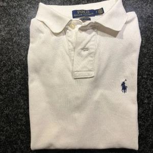 POLO RALPH LAUREN BASIC- PIKÉ - WHITE - Tja!  Storleken är Small, och trots ett års användning fortsätter tröjan att vara en perfekt passform. Med ett ursprungligt pris på 1 395 kr och ett år av uppskattning erbjuder jag nu denna stilsäkra tröja för 449 👍Pris kan diskuteras vid snabb aff