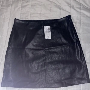 Skinnkjol fejk - Kjol i läderimitation, storlek L. Oanvänd.  Dold Dragkedja i sidan