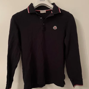 Moncler långärmad piké - Svart långärmad pikétröja från Moncler, använt skick och väl omhändertagen. Nypris 3.910:- säljer för 1.100:- 