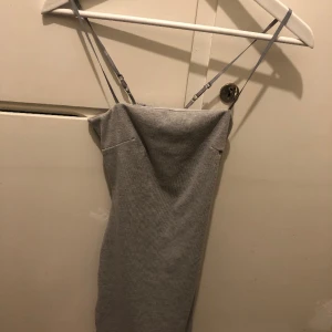 Klänning - Grå klänning med reglerbara band, dubbeltyg på framsidan, öppen rygg. Formar sig fint. Passar en strl xs liten s.