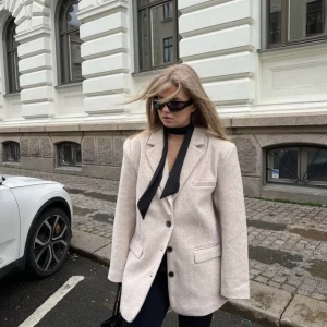 Blazer - En beige varmare blazer från Nelly. Perfekt som jacka i höst och vinter. Helt oanvänd då den tyvärr var för stor för vad jag gillar. Prislappen kvar i storlek 32 men skulle mer säga det är en 34 då den är oversized. 