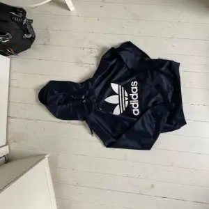 Köp två så bjuder jag på frakten!! En svart jacka från Adidas med en stor vit logotyp på framsidan. Jackan har en huva och dragsko vid halsen. materialet är glansigt och jättefint! 