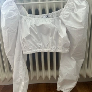 Vit bolerotopp från NA-KD - En vit bolerotopp från NA-KD med långa puffärmar och elastiska kanter vid ärmslut och nederkant. Toppen har en lös passform och är tillverkad i ett lätt och luftigt material.