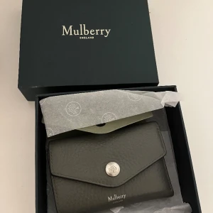 Mulberry plånbok - Mulberry envelope logo Wallet i grå med silver detaljer och brun insida.  Många fack för både sedlar, mynt och kort.  Fint använt skick, lite skav på insidan och på märket Nypris ca 3400:- OrginalBox medföljer  Skicka meddelande för mer info/ bilder