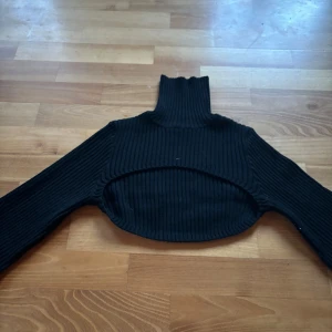 Svart ribbad croppad polotröja - Säljer en snygg svart ribbad polotröja som är croppad. Perfekt för höst och vinter! Tröjan har långa ärmar och en hög polokrage som håller dig varm och stilren. Passar både till vardags och fest. 🖤