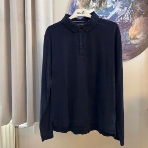 Mörkblå pikétröja från Tommy Hilfiger - Säljer en snygg och stilren mörkblå pikétröja från Tommy Hilfiger. Tröjan är i storlek XXL och är gjord av 100% bomull vilket gör den superbekväm att ha på sig. Den har långa ärmar och en klassisk krage med knappar. Perfekt för både vardag och lite finare tillfällen!