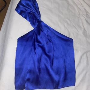 Blå sidenklänning från NA-KD - Säljer en superfin blå topp från NA-KD i storlek 36. Toppen är gjord av siden och har en oneshoulder-design som ger en elegant look. Perfekt för fest! 💙