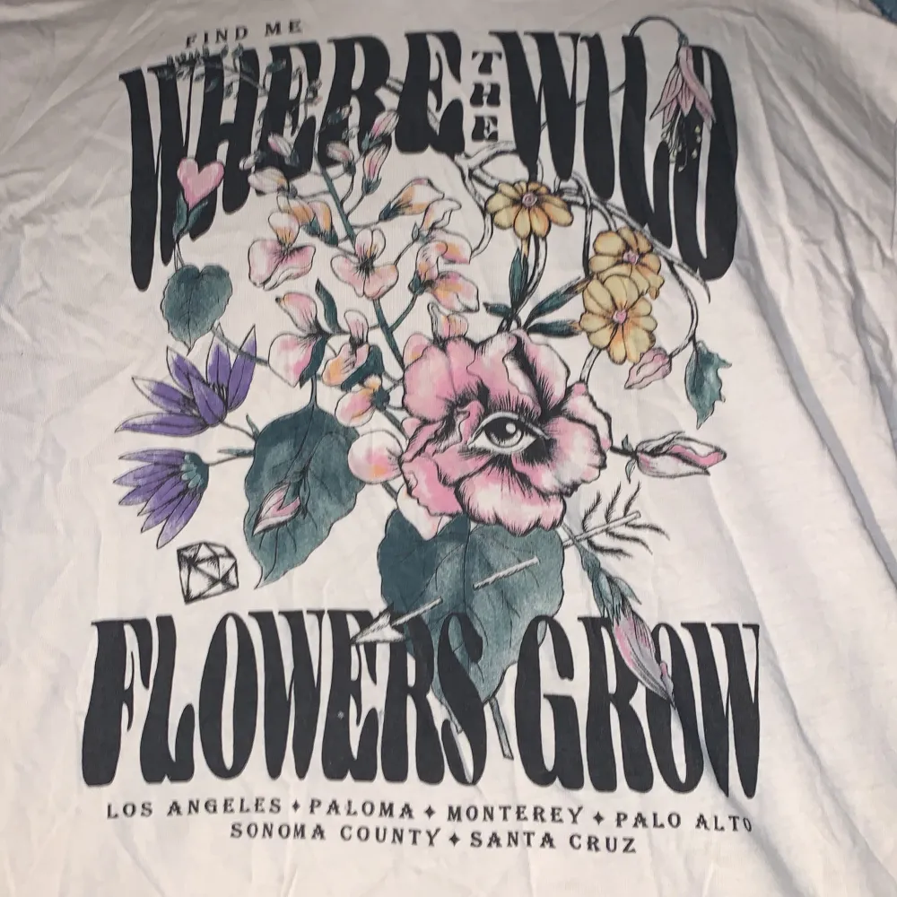 Säljer en beige t-shirt med ett coolt blommigt tryck och texten 'Find me where the wild flowers grow'. Den är i storlek Xs. Perfekt för en avslappnad och stilren look. Passar bra till både jeans och shorts!. T-shirts.