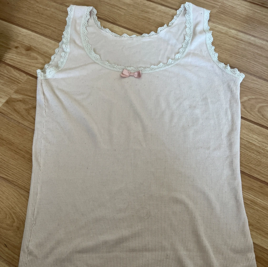 Vit ärmlös topp med spetsdetaljer och rosett