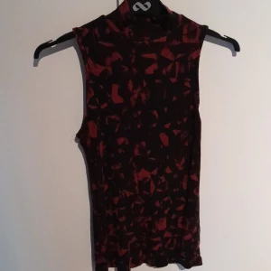 Polotröja utan ärmar - En svart och röd polotröja utan ärmar. Storlek S men passar M/L också.