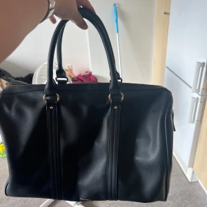 Svart handväska från Anna Field - Säljer en snygg, stor och rymlig svart weekendbag från Anna Field. Väskan är gjord av skinn och har två handtag för enkel bärning. Medföljer axelrem.