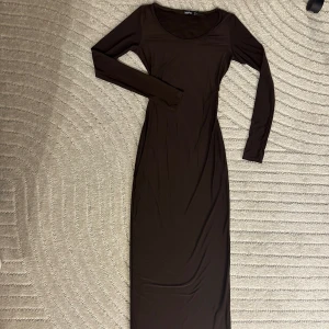 Brun långärmad maxiklänning - Jättefin brun maxiklänning som kramar om kroppen. Den är helt ny och oanvänd.
