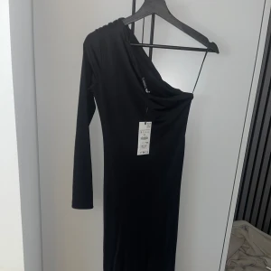 Klänning Zara - Svart klänning från zara med en arm. Aldrig använd, prislapp kvar. Slit på sidan, inte tight. 