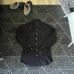 Ralph lauren skjorta - Skjortan är i en populär färg med ett lila märke riktigt snygg. Den är i jättebra skick och verkligen prisvärd. Hör av er