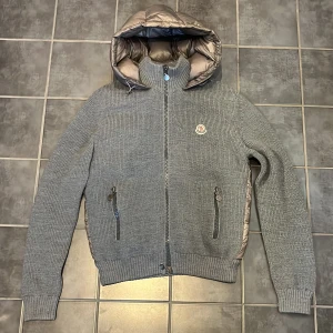 Moncler cardigan  - Snygg Moncler cardigan i bra skick Defekt visas ut på bilden med penna. några lagade håll på bröstet som knappt syns och lite sliten inuti. Men förutom de så är den jättefint skick. Storlek L men passar M. Kom PM om det är något ni undrar över🙌