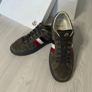 Moncler Skor - Tja säljer nu ett par gråa skor från Moncler! Nypris ~5500kr mitt pris 1999kr. Skick 9/10 väldigt omhändertagna. Storlek 41 passar även 42. Allt og inkl dustbag, skolåda. Priset är ej hugget i sten!