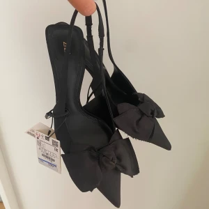 Svarta slingbacks  - Svarta slingbacks med rosett från Zara. Aldrig använda, prislappen kvar. Sann till storlek. 