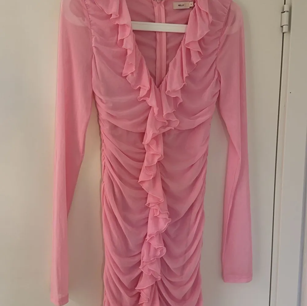 Rosa klänning från NELLY som är perfekt till sommaren,midsommar,avslutningar🩷 Den är i jätte bra skick då den bara är använd en gång, storlek S🎀Jätte fina volanger och klänningen sätter sig så fint på kroppen🎀  Skriv för fler frågor!. Klänningar.