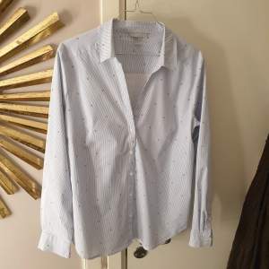 Ljusblå randig skjorta med små körsbär från H&M. Aldrig använts. Storlek 46, men passar mer som en 42/44. Skönt strechigt material 