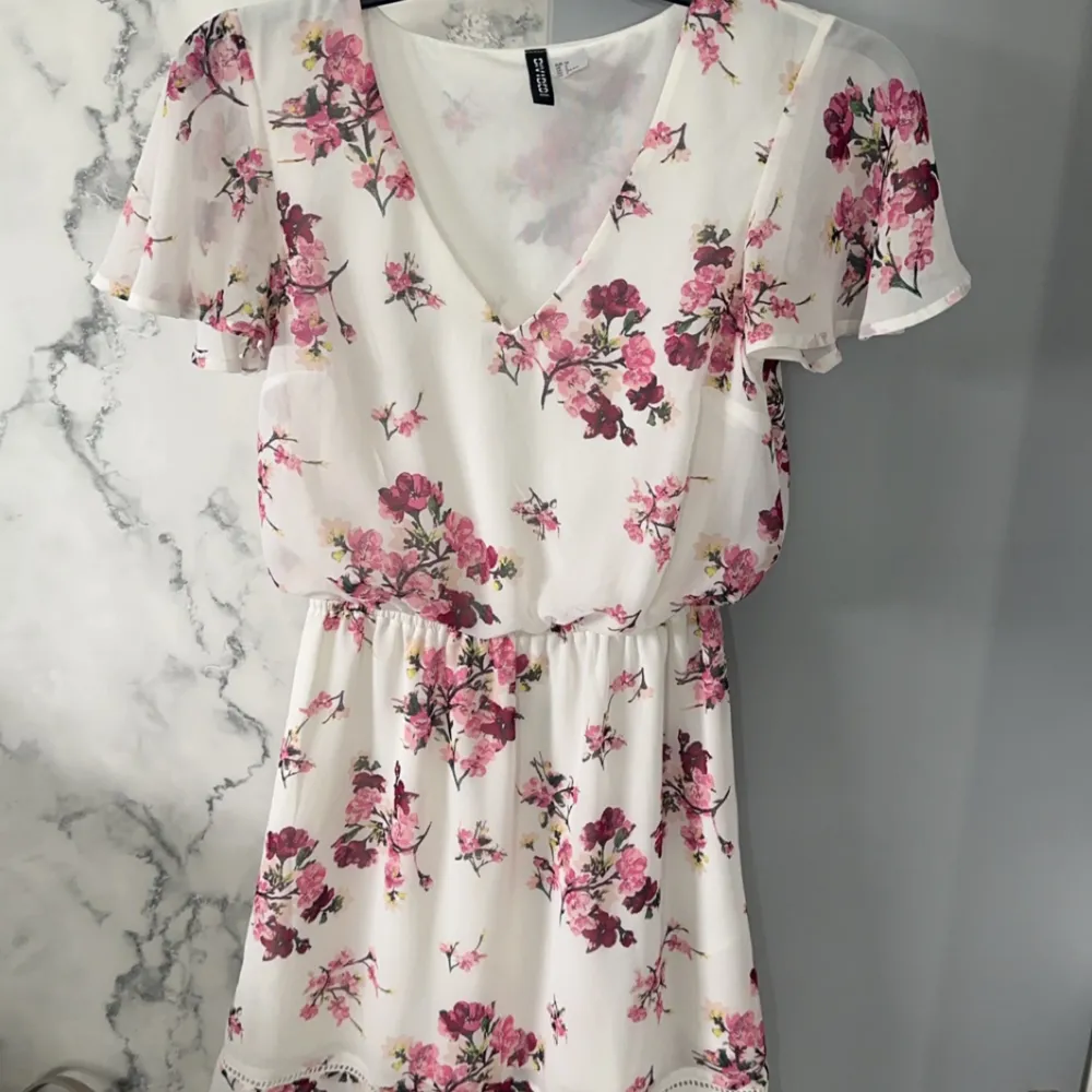 En jätte söt vit klänning med rosa blommor, perfekt till våren och sommaren!🌸 Säljer pga för liten för mig tyvärr. Klänningen är använd ett fåtal gånger utan några som helst defekter. . Klänningar.