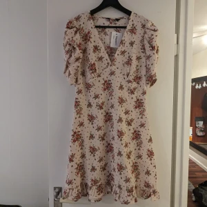 Helt ny sommarklänning. - Helt ny jättefin klänning! Beige med blommor och fina detaljer. 