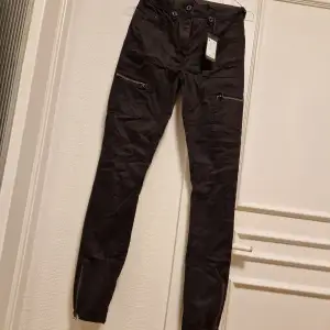 Strechiga rockiga helt nya svarta G-star jeans med prislapp kvar ny pris 1050 kr. Midja 24 och längd 33.  Zip på 2 lårfickor och även blixtlås på båda nedre sidorna av byxbenen. 