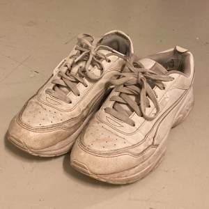 Vita skor med märket puma. Har flera olika defekter som hålet på sisa bilden och att de är allmänt smutsiga, därav priset.