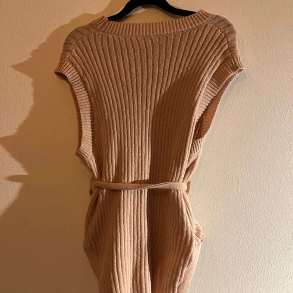 En beige ärmlös väst med snörning vid midjan♥️ Storlek: S♥️ ♥️♥️♥️. Neuletakit & Villapaidat.