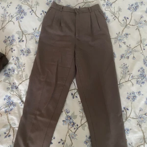 Kostymbyxor med veck - Superina bruna kostymbyxor med veck, något korta i benen, köpta second hand men ursprungligen från Danmark✨