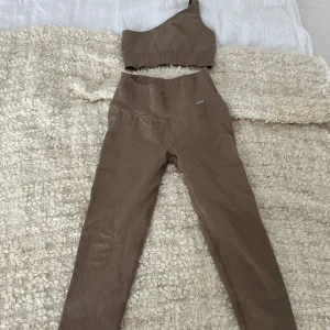 Aimn set - Säljer ett aimn set i färgen espresso, byxorna är Espresso Ribbed Seamless Tights och sen tillhörande one shoulder sport-bh i färgen espresso💕I princip oanvänt. Köpare står för frakten.