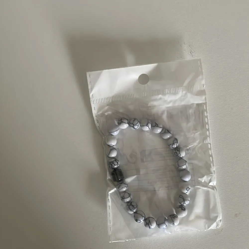 Två armband med pärlor, ett i grått och ett i vitt med grå marmorering. Båda armbanden har elastiska band för enkel passform. Ett armband för 49 två för 59. Pris går att diskutera . Asusteet.