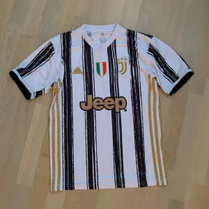 Juventus hemmatröja 20/21 Ronaldo 7 - Juventus hemmatröja från säsongen 2020/21 med Ronaldo 7 där bak. Tröjan är använd men i helt perfekt skick, den är riktigt fet och är storlek 176 men passar även storlek s, xs och m